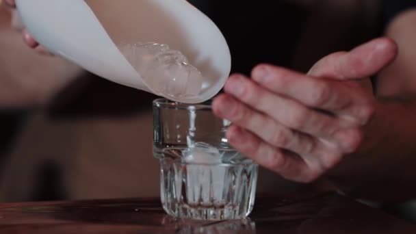 .De barman giet gemalen ijs in een glas. close-up — Stockvideo