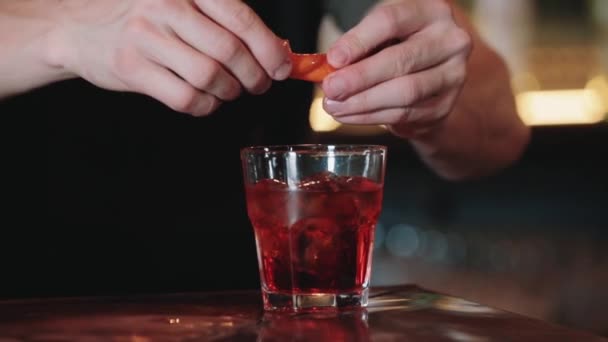 O close-up de um barman aperta o suco de laranjas enquanto prepara um coquetel alcoólico. Close-up. Negroni — Vídeo de Stock