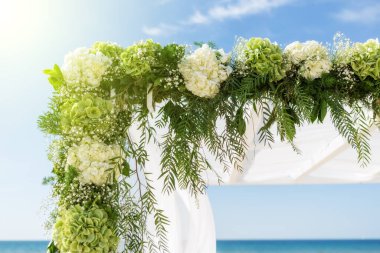 Düğün kemeri için çiçek toplayın. Gökyüzünün, denizin ve güneşin arka planında.