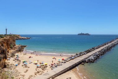 Portimao limanının girişindeki sahilde turistler.