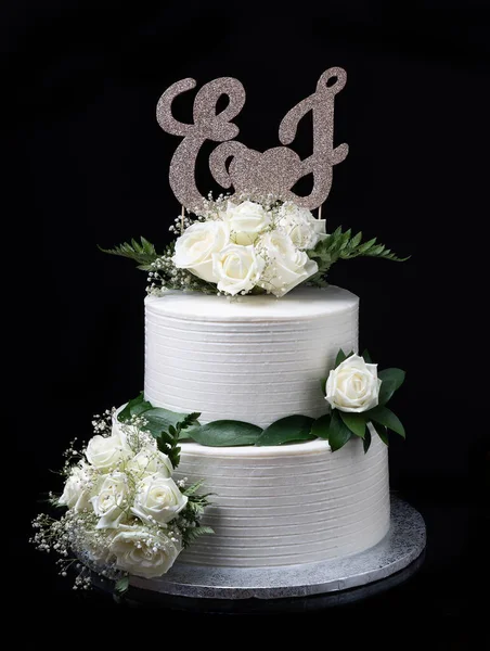Elegant wedding cream cake, on a black background. With roses