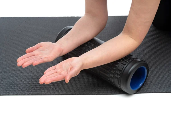 Een vrouw van middelbare leeftijd op een myofasciale roller maakt een handmassage op een witte achtergrond. — Stockfoto