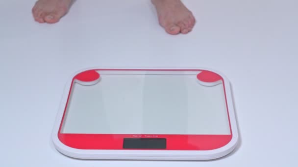 Une femme obèse d'âge moyen se tient sur les balances pour peser avec ses pieds nus. Vue latérale . — Video