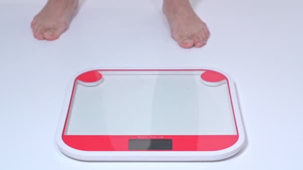 A middle-aged obese woman stands on the scales for weighing with her bare feet. Side view. — Stock Video