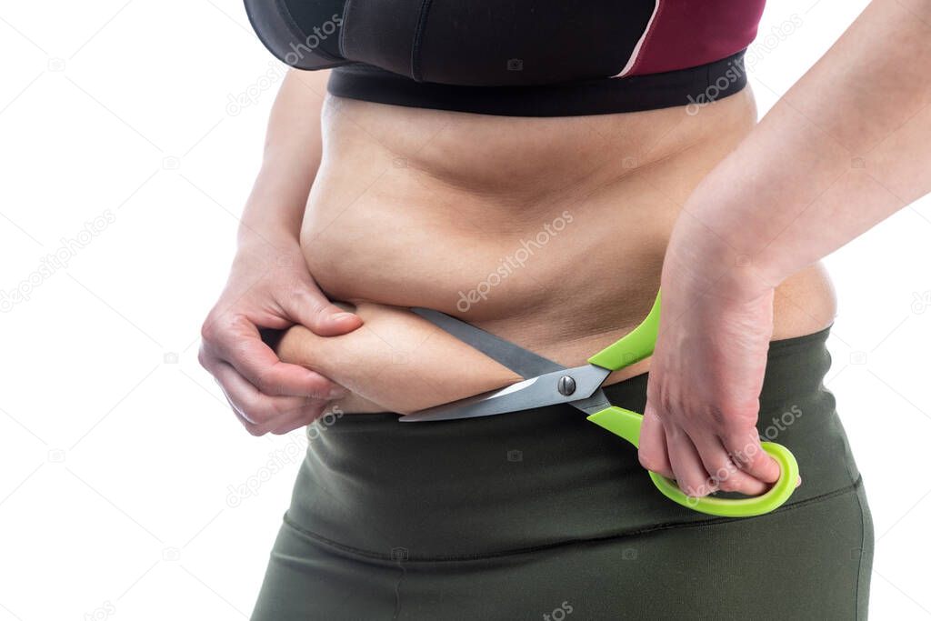 Middle-aged woman with obesity and saggy skin of the abdomen, on a white background, close-up. Scissors as a symbol of surgical retraction.