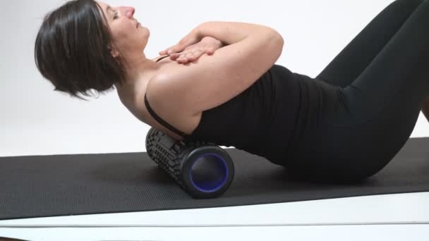A middle-aged woman is doing a backbone massage on myofascial roller. Close-up. — Stock Video