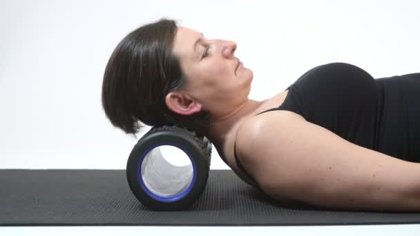 Una donna di mezza età massaggia la colonna vertebrale, il collo e gira la testa su un tappeto miofisico. Primo piano . — Video Stock