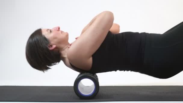 Una mujer de mediana edad está haciendo un masaje de columna vertebral en el rodillo miofascial. Primer plano . — Vídeos de Stock