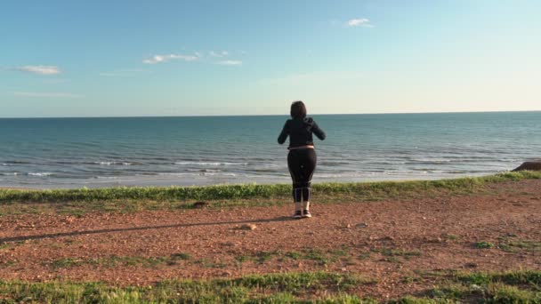 Donna felicemente di mezza età con obesità che fa ginnastica sull'oceano. Rallentatore . — Video Stock