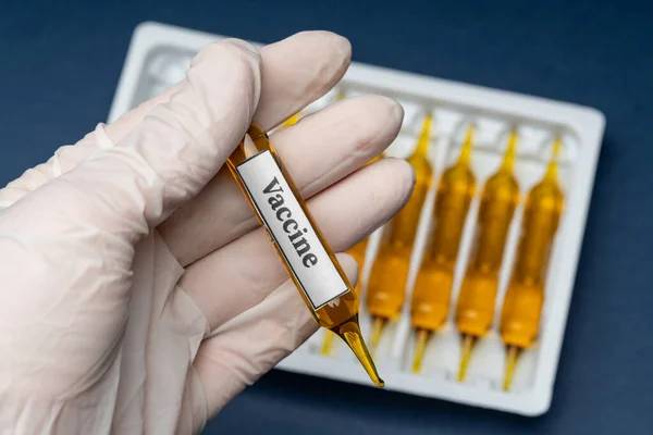 Lékařské kapsle z viru koronaviru na stole a v ruce na modrém pozadí. — Stock fotografie