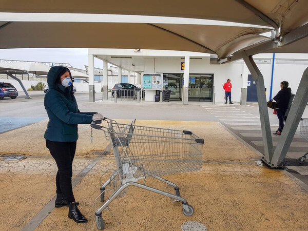 Portugal Faro 2020 8 -April: Woman with a shopping cart standing in line at a store shopping on the street during the virus covid 19.
