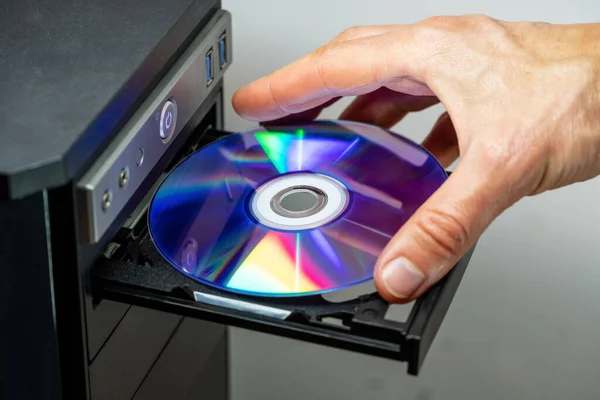 Hand inserting DVD into a computer. Closeup. — Stock Photo, Image