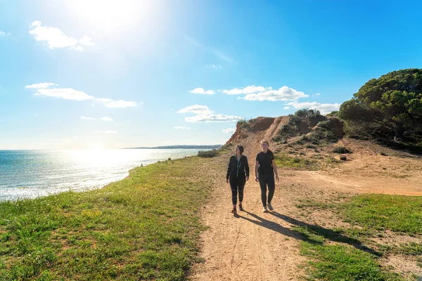 Dwie dziewczyny sportowców w mundurach sportowych, spacer wzdłuż brzegu klifu, w lecie w pobliżu morza. Plaża Falesia, Vilamoura Albufeira, Portugalia. — Zdjęcie stockowe