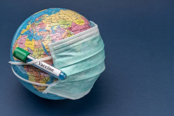 Lékařská maska je umístěna na zeměkouli s zkumavkou vakcíny proti koronaviru a alergiím. — Stock fotografie