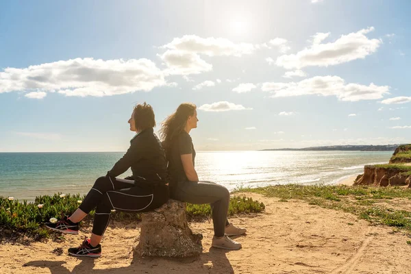 Sport dziewczyna i kobieta na brzegu Oceanu Atlantyckiego Portugalii, siedzi na kamieniu i mówi i myśli o życiu. — Zdjęcie stockowe