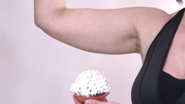 Una donna di mezza età, con la pelle cadente sulla mano, tiene un cupcake con l'altra mano, su uno sfondo bianco . — Video Stock
