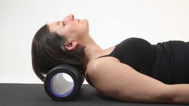 A middle-aged woman massages her spine, head, neck back and forth on a myofisial rug. Close-up. — Stock Video