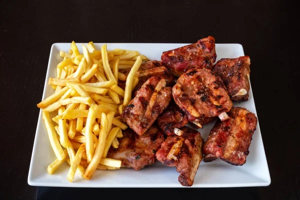 Fried, juicy chicken with french fries on a white plate. Dark black background. — Stock Photo, Image