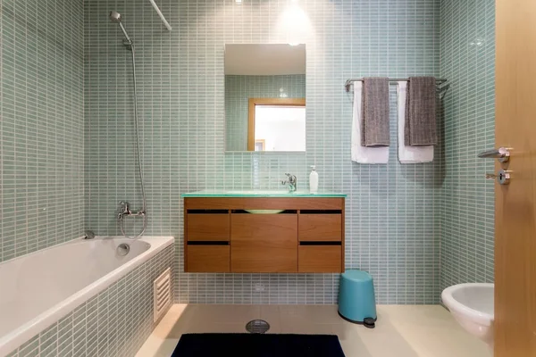 Baño moderno con bañera, mesita de noche, espejo. Diseño de hotel hermoso europeo dentro . — Foto de Stock