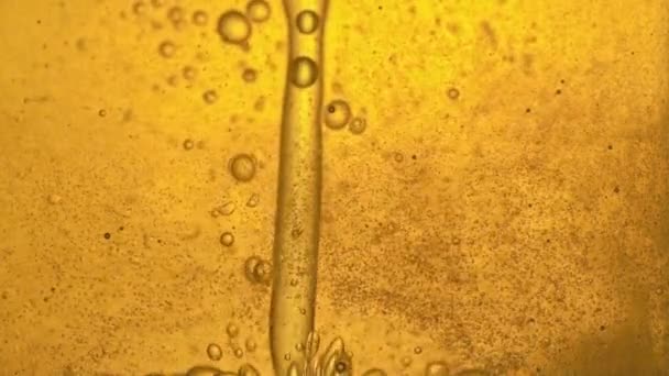 Bränsle, olja, gul gyllene nyans, med rörliga bubblor, upp och ner, i laboratoriets glaskärl. Kopiera utrymme. — Stockvideo