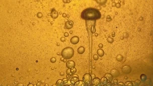 Carburant, huile, teinte dorée jaune, avec bulles mobiles, de haut en bas, dans le récipient en verre du laboratoire. Espace de copie .