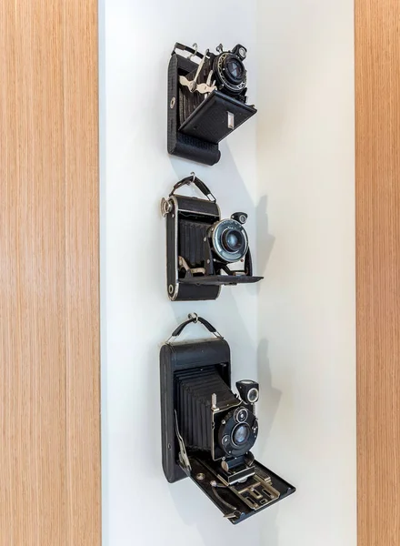 Vintage kamery s černým koženým pouzdrem zavěšeným v rohu na bílé stěně. — Stock fotografie