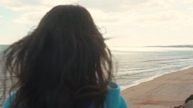 Okyanus kıyısındaki genç bir turist elinde telefonla etrafındaki manzaranın resimlerini çekecek..