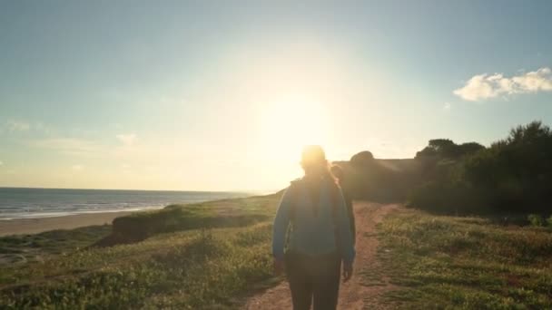 Sportlich erfolgreiche Touristinnen spazieren an einer Klippe am Meer entlang. Mutter mit einer Tochter. — Stockvideo