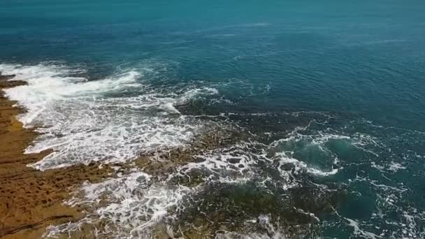 Türkisfarbenes Wasser im Meer wiegt sich in Wellen an felsigen Küsten. Luftbild in Zeitlupe. — Stockvideo