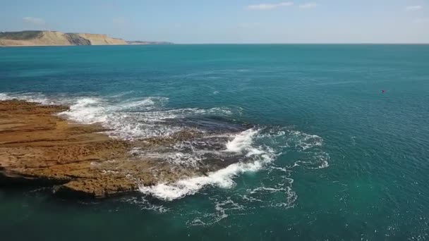 Ностальгическое аэровидео, в замедленном движении моря, волны плавно катятся по скальным шортам Тихого Атлантического океана. — стоковое видео
