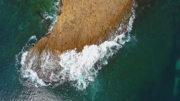 El agua turquesa en el mar se balancea en olas a orillas rocosas. Video aéreo en cámara lenta . — Vídeo de stock