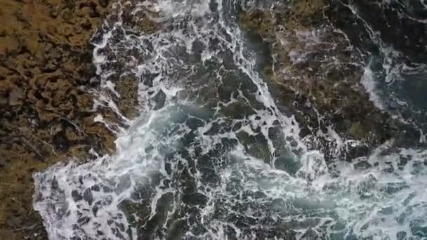 El agua turquesa en el mar se balancea en olas a orillas rocosas. Video aéreo en cámara lenta . — Vídeos de Stock