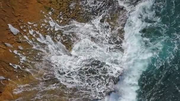 Turkoois water in de zee zwaait in golven op rotsachtige kusten. Luchtfoto in slow motion. — Stockvideo