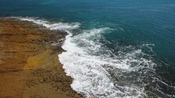 Turkoois water in de zee zwaait in golven op rotsachtige kusten. Luchtfoto in slow motion. — Stockvideo