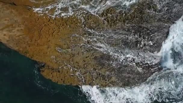 Tyrkysová voda v moři se houpe ve vlnách na skalnatých březích. Letecké video ve zpomaleném filmu. — Stock video