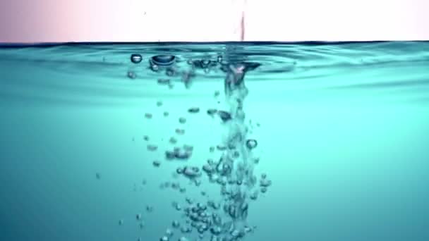 Verter agua transparente y transparente en un líquido azul, agitar, en un recipiente de vidrio que crea bombillas. Primer plano . — Vídeo de stock