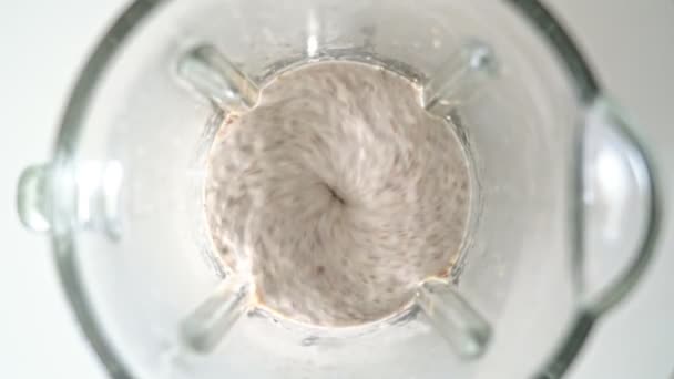 Liquidificador elétrico, um misturador que chicoteia dentro de uma tigela de vidro de smoothie, mingau de cereal. Close-up. Vista superior . — Vídeo de Stock