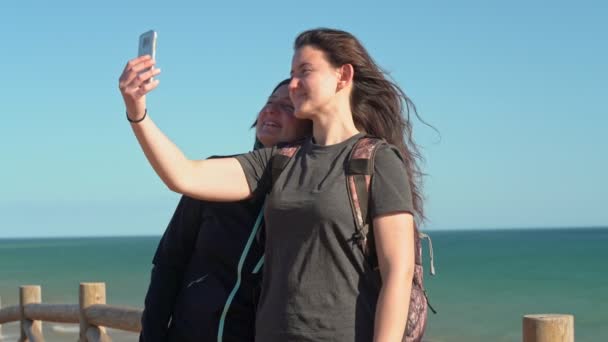 Éxito, mujer de mediana edad con una chica joven, en un acantilado cerca del océano, selfie por teléfono. Portugal. Vilamoura. Madre con hija . — Vídeo de stock