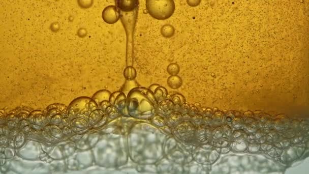 Carburant, jaune, huile dorée, versé dans un récipient en verre dans un laboratoire, libère des bulles semblables à de la mousse.