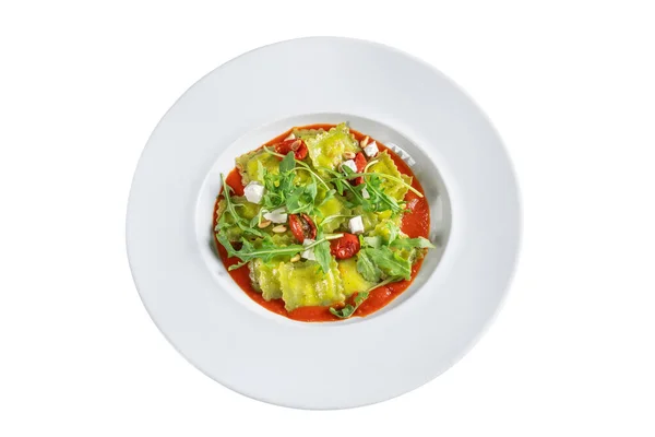 Italiensk rätt av ravioli i tomatsås, med ruccola på en tallrik. På vit bakgrund. — Stockfoto