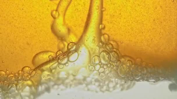 Paliwo, żółty, złoty olej, wlewany do szklanego naczynia w laboratorium, uwalnia pęcherzyki podobne do pianki. — Wideo stockowe