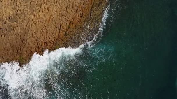 Vidéo aérienne nostalgique, au ralenti de la mer, les vagues roulent en douceur sur les rives rocheuses de l'océan Pacifique Atlantique.