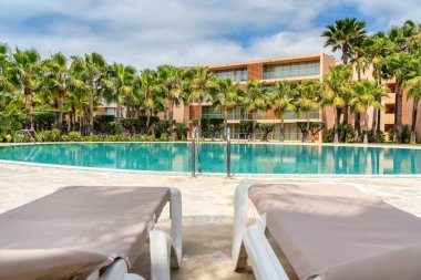 Temiz, berrak, mavi su ve güneş pansiyonlu modern lüks havuz..