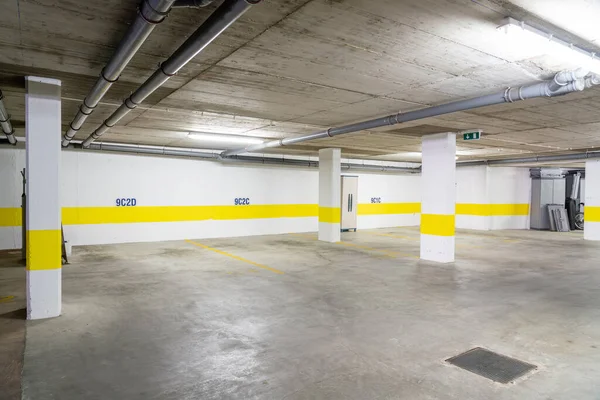 Společná garáž pro parkování aut ve vícepodlažní budově s kanalizačními trubkami. — Stock fotografie