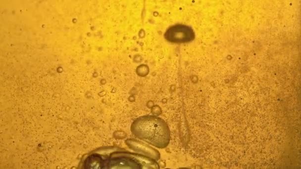 Treibstoff, gelbes, goldenes Öl, das im Labor in ein Glasgefäß gegossen wird, verteilt die Blasen und bläst einen Strahl. — Stockvideo