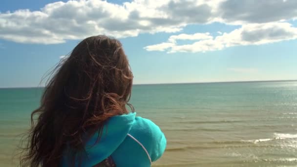 Jong meisje toerist op het strand door de oceaan met een telefoon in zijn hand zal foto 's van het landschap om hem heen te nemen. — Stockvideo