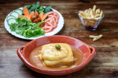 Kil tabakta Portekiz francesine salata ve ahşap arka planda kızarmış patates..