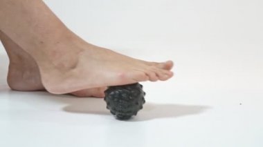 Orta yaşlı bir kadın miyopsi topuyla ayak tabanına masaj yapıyor. Yakın plan..