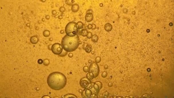 Carburant, huile, teinte dorée jaune, avec bulles mobiles, de haut en bas, dans le récipient en verre du laboratoire. Espace de copie .