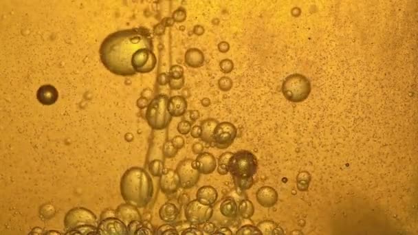 Carburant, huile, teinte dorée jaune, avec bulles mobiles, de haut en bas, dans le récipient en verre du laboratoire. Espace de copie .